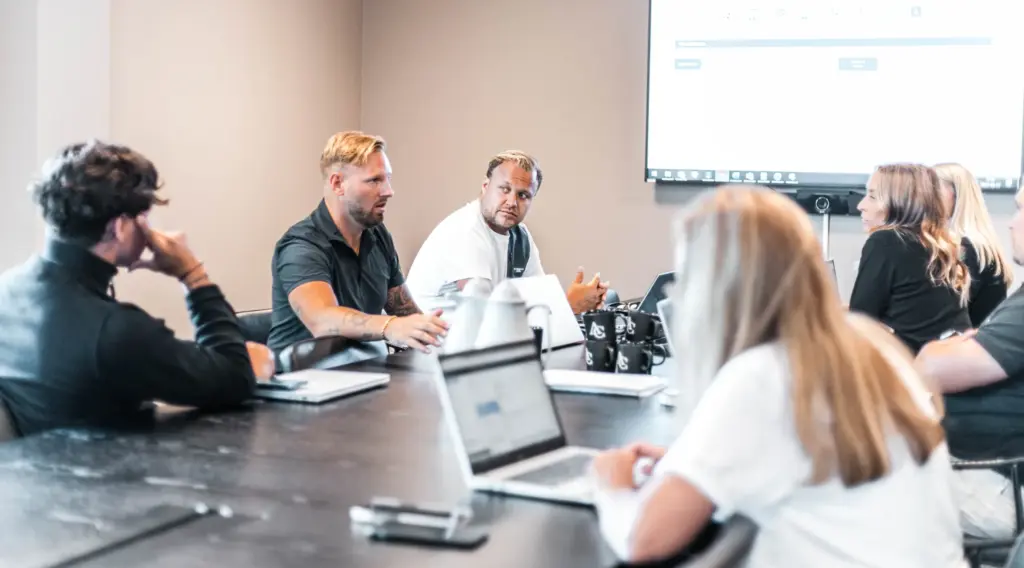 People in a meeting around a large table with laptops.
